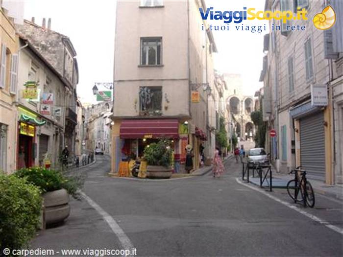 Narrow street with old buildings, colorful shop signs and parked bicycle in Arles