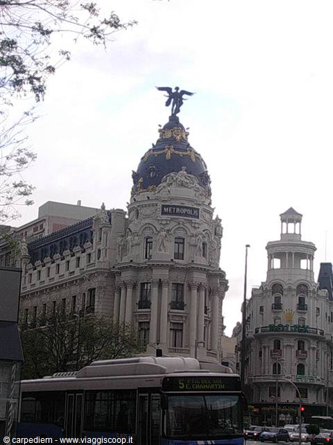 Metropolis Building in Madrid with dome and golden angel, city bus in front
