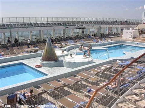 Pool deck on a cruise ship with sun loungers and passengers relaxing
