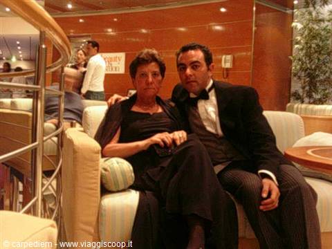 Couple in tuxedo and black dress on sofa in ship lounge