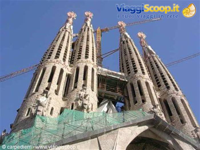 Sagrada Família towers in Barcelona with cranes and scaffolding against a blue sky