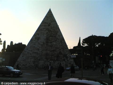The Pyramid of Cestius in Rome, brick and marble, pedestrians and cars in morning light