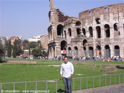Tourist in white shirt poses on the lawn in front of the Colosseum