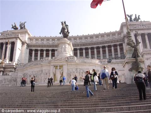 Tourists climbing Vittoriano marble steps, equestrian statue, white stone, flag
