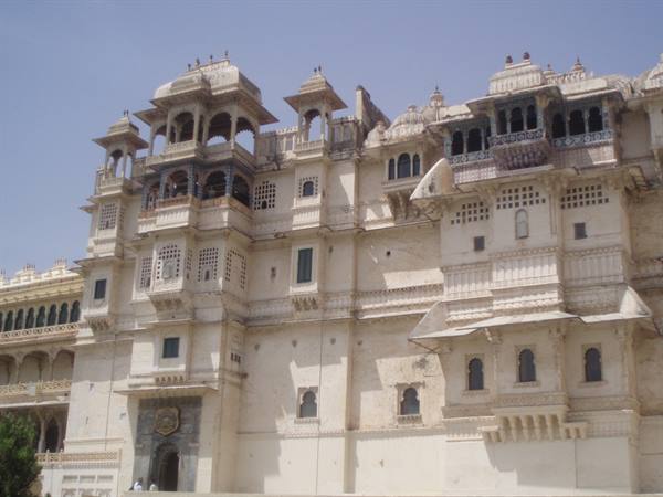 White facade of Udaipur City Palace with balconies and chhatris under blue sky