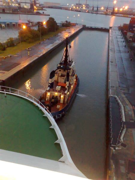 Tugboat turning in the port canal, evening lights on the piers