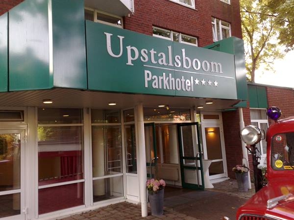 Entrance of the Upstalsboom Parkhotel, green sign on red bricks, vintage red car