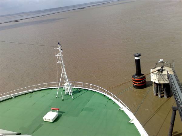Ferry green bow moored at black and red bollard in harbor