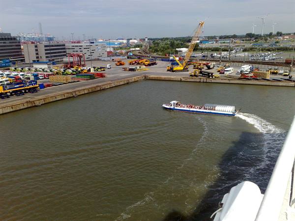 Passenger ferry crossing the harbor basin among cranes and yellow trucks