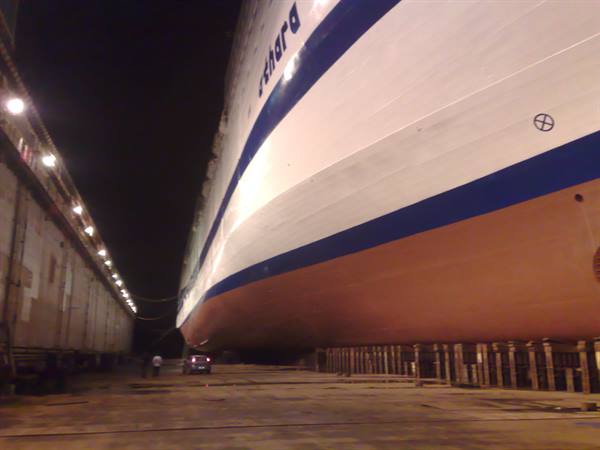 The Da Vinci ship in dry dock at night, red hull resting on blocks