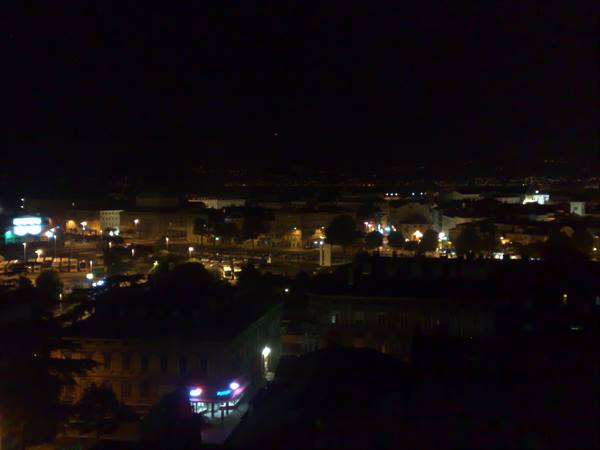 City lit up at night, streetlights and neon signs among dark buildings