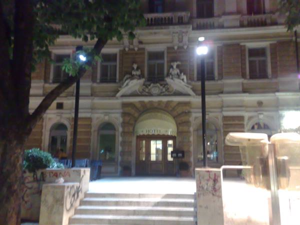 Night facade of historic hotel with steps, lit lamps and stone ornaments