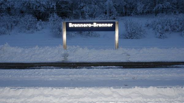 Illuminated Brennero-Brenner sign beside snowy railway tracks