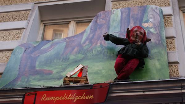 Rumpelstilzchen figure on painted forest signboard above a shop window
