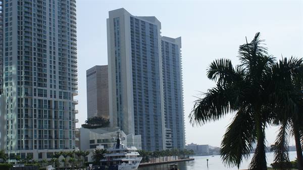 Glass towers along the canal, moored yachts and palm trees in Miami