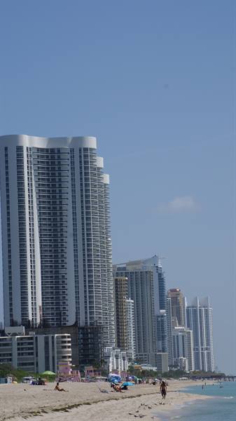 White towers over Miami Beach, tourists under umbrellas, blue sky