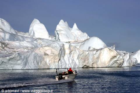 Motorboat with fisherman beside huge icebergs in Ilulissat