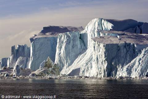 Massive icebergs rising above calm dark water, Ilulissat