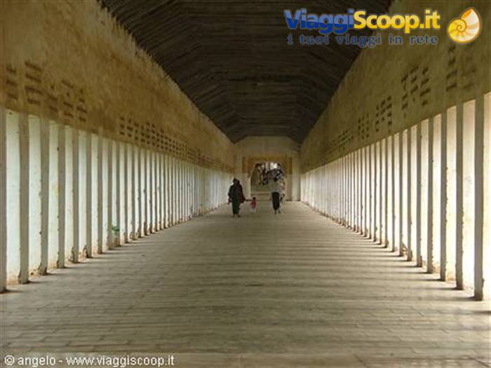 Long corridor with rows of white columns, ochre walls, few walkers