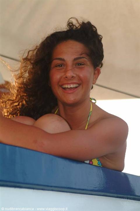 Smiling girl with curly hair leaning on the boat's blue rail