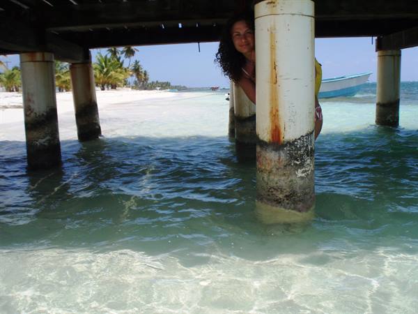 Woman between concrete pier pillars, turquoise water and a boat
