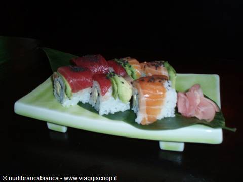 Green dish with tuna and salmon uramaki sushi, pickled ginger, nighttime light