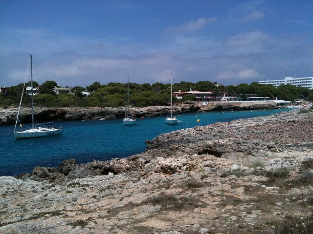 Vele ancorate in caletta rocciosa con acqua turchese e pineta, Maiorca