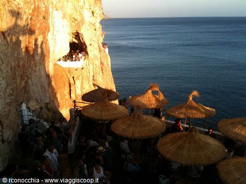 Straw umbrellas on a cliffside terrace carved in rock, Cova d'en Xoroi