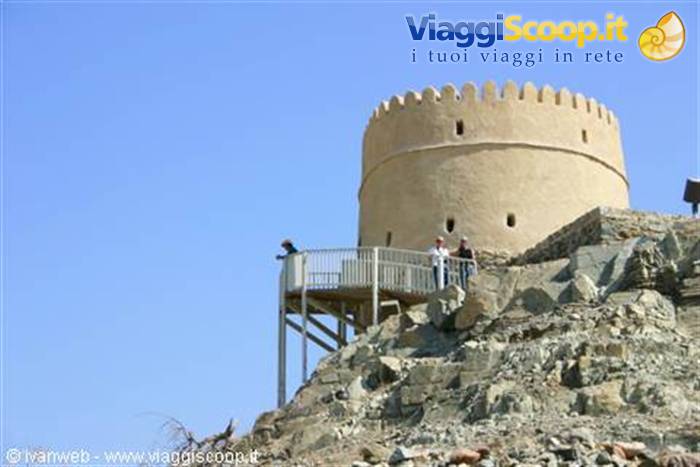 Tourists on the walkway toward the round stone tower of Muttrah Fort