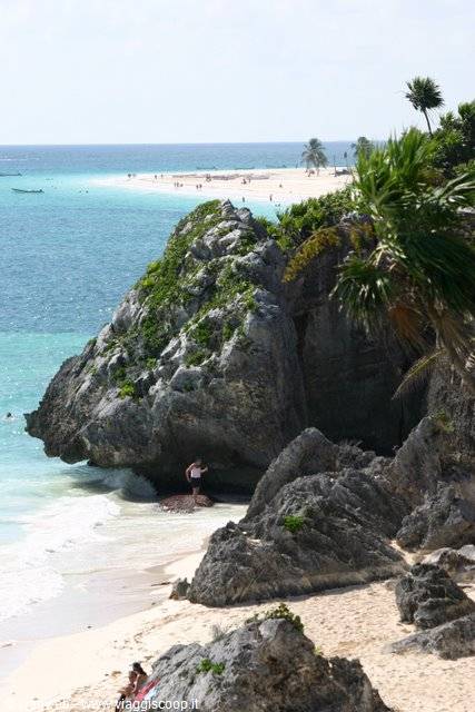 Limestone cliff with palms and tourists on Tulum beach