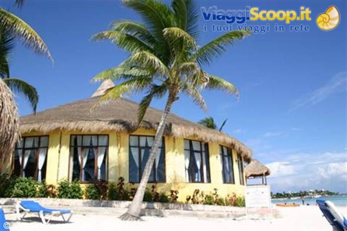 Leaning palm tree in front of yellow thatched-roof hut on white beach