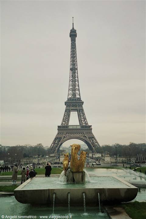 Iron Eiffel Tower behind the golden Trocadero fountain, grey sky