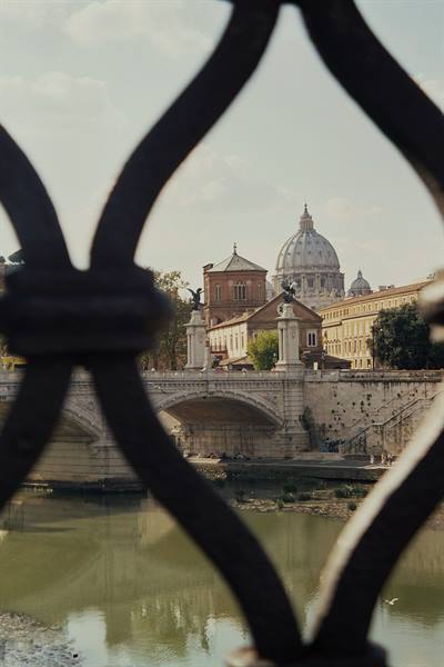 St. Peter's dome and Tiber bridge seen through a wrought-iron railing
