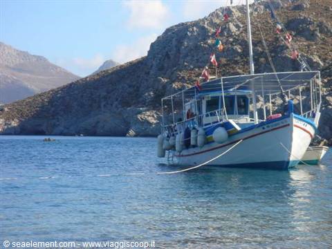 White and blue fishing boat moored in rocky bay, Greece