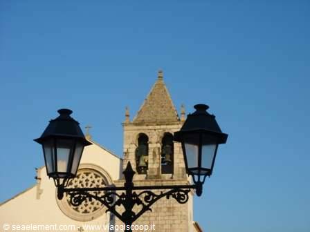 Iron lanterns in front of the bell tower and white church facade