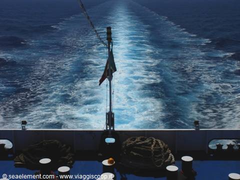 White wake trail behind the ship, flag on mast and ropes on deck