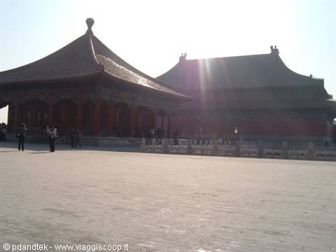 Tiled-roof pavilions in the Forbidden City, visitors walk under bright sunlight