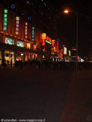 Neon signs lighting Wangfujing shopping street at night, pedestrians walking by