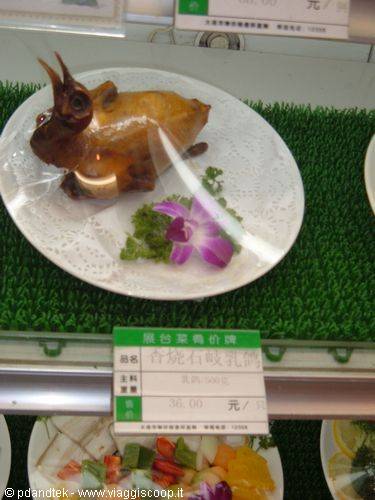 Whole roasted pigeon on white plate, Chinese restaurant display