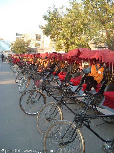 Pedicabs with red canopies lined up along the road, Beijing