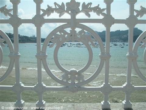 White wrought-iron railing of La Concha, bay with boats in San Sebastián