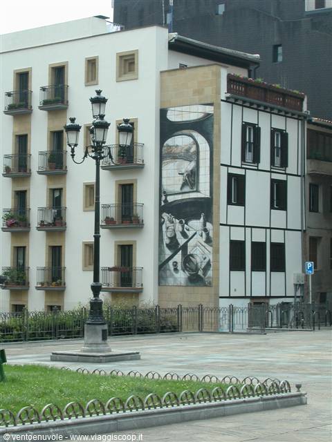 Cast iron lamppost in front of buildings with a ceramic mural, Pamplona