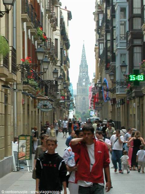 Crowded pedestrians on pedestrian street with gothic cathedral spire in background