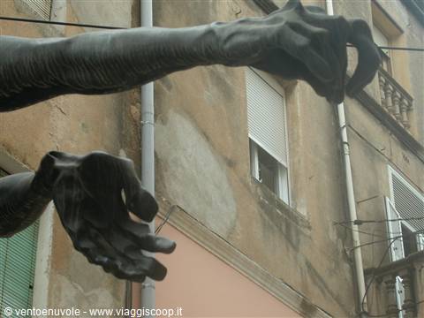Sculpted metal hands emerge from a crumbling building facade