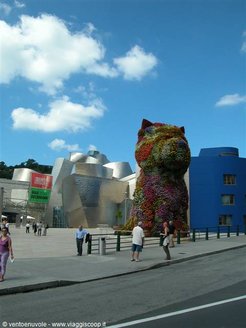 Flower Puppy sculpture outside Guggenheim Bilbao, tourists strolling under blue sky