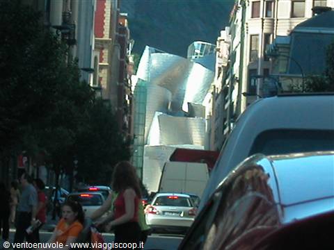 Guggenheim Museum Bilbao seen between buildings, titanium curves, street traffic