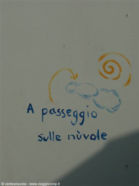Handwritten on a gray wall: 'A walk on the clouds', with painted sun and clouds