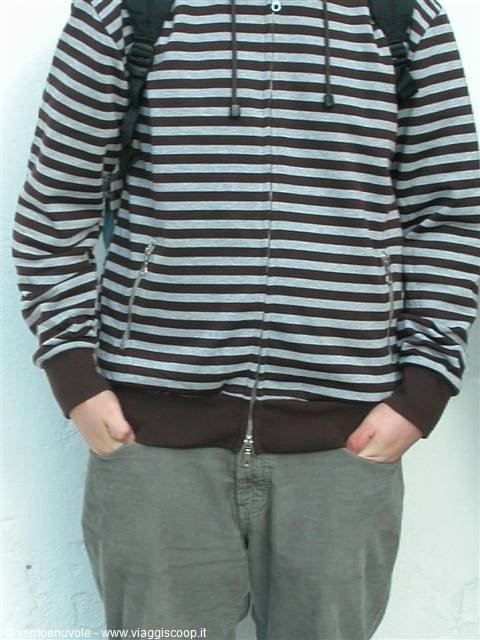 Young person in brown striped hoodie with backpack, hands in pockets