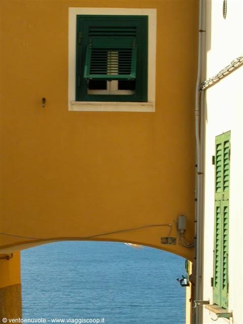Yellow house with green shutters and arch opening onto the sea