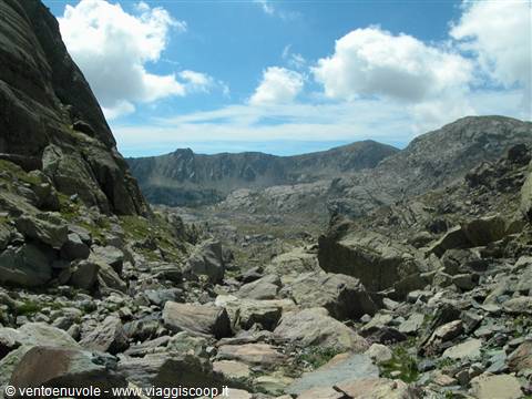 Granite moraines among mountains under white clouds and blue sky